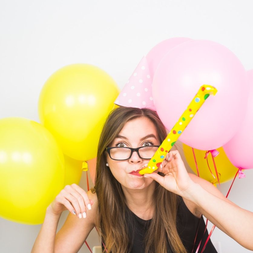 mujer con serpentina y globos amarillos y rosas